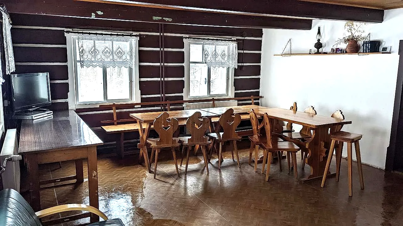 Společenská místnost s roubenými stěnami a dlouhými stoly